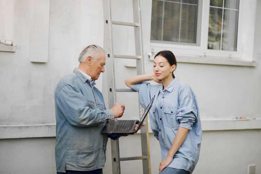 a girl teaching her grandfather to use a laptop